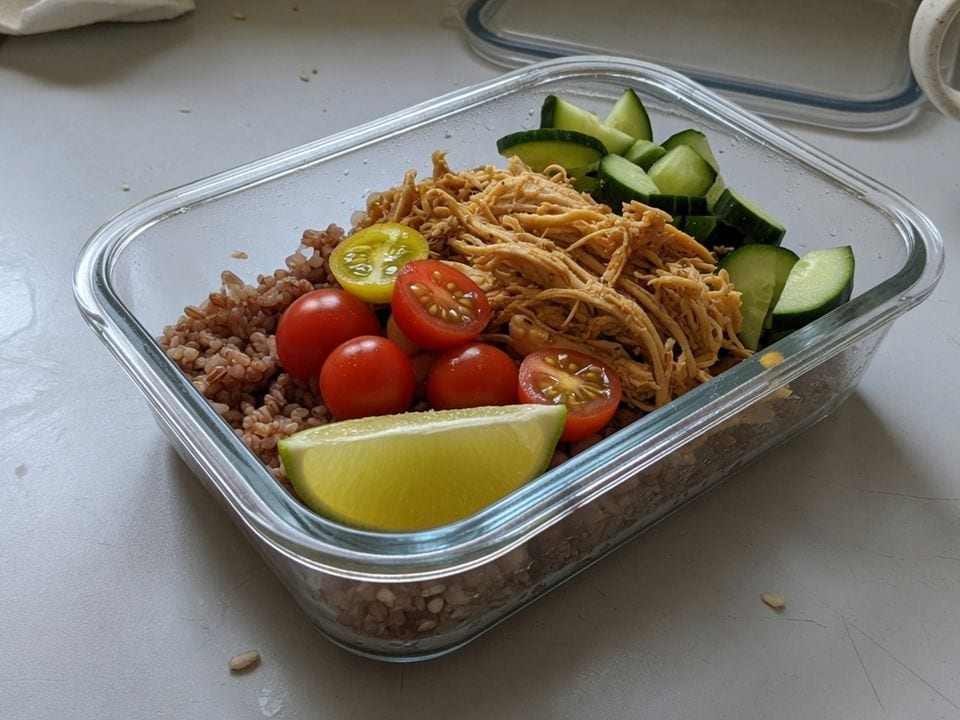 Refeição prática de arroz integral, frango desfiado, tomate, pepino e limão.
